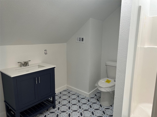 bathroom with toilet, vanity, and vaulted ceiling