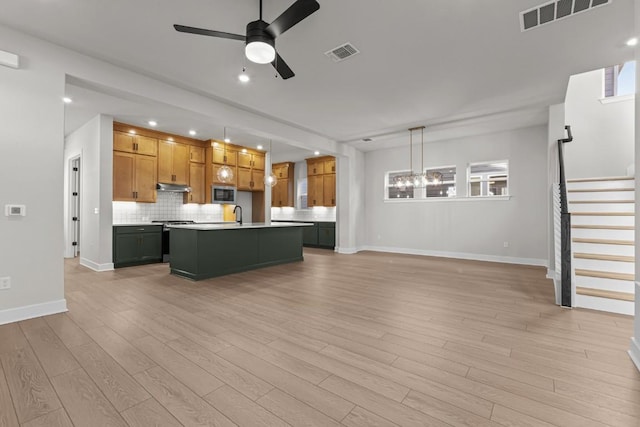 unfurnished living room with ceiling fan with notable chandelier, light hardwood / wood-style floors, and sink