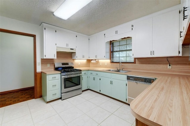 kitchen featuring sink, stainless steel gas range oven, white cabinetry, white dishwasher, and decorative backsplash