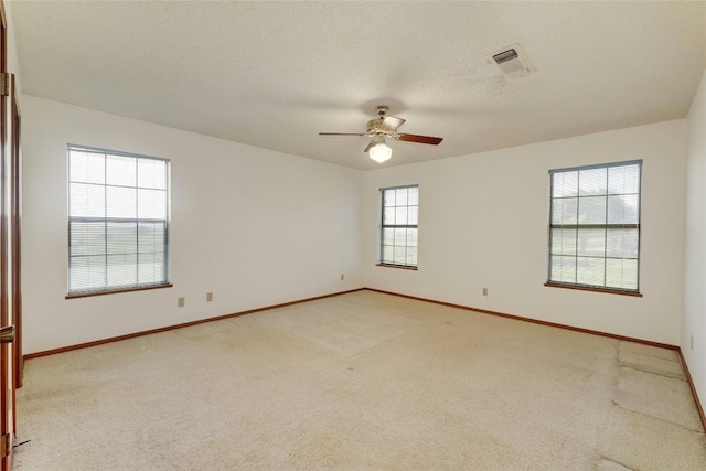 spare room with ceiling fan, light colored carpet, and a textured ceiling