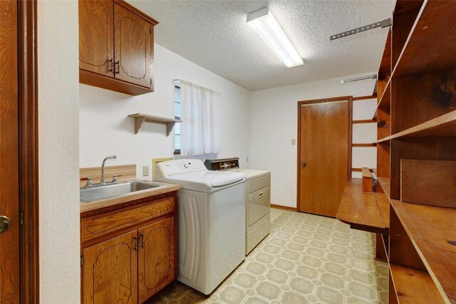 laundry room featuring sink, independent washer and dryer, cabinets, and a textured ceiling