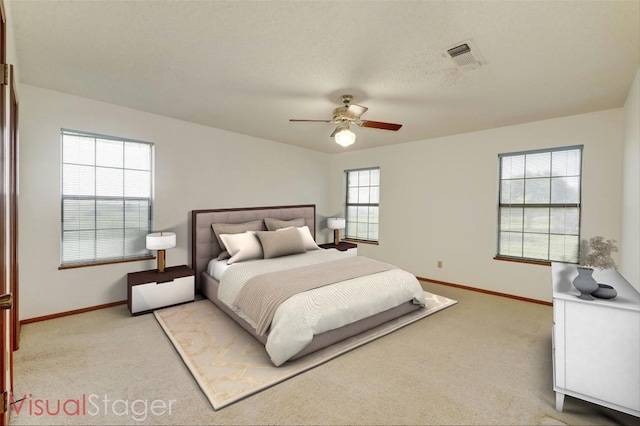 bedroom with ceiling fan, light carpet, and a textured ceiling