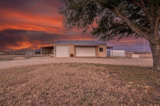 garage at dusk featuring a carport and a lawn