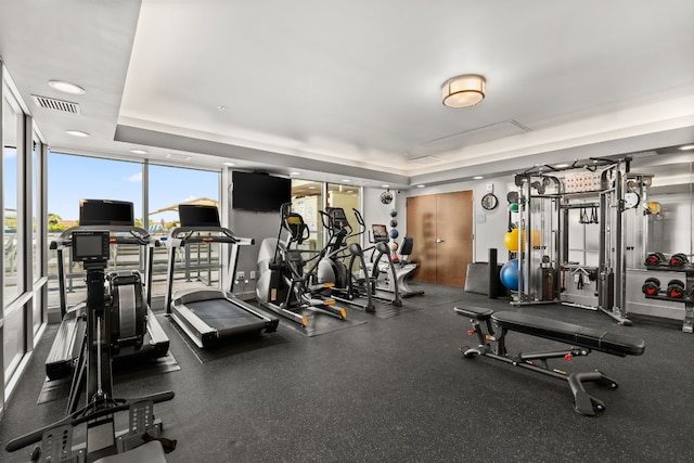 gym with expansive windows and a tray ceiling