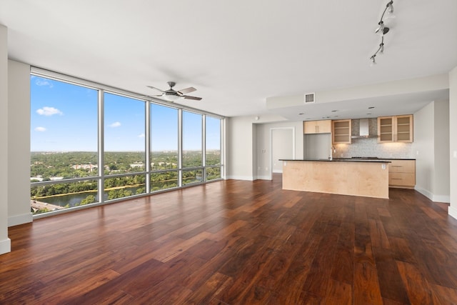 unfurnished living room with ceiling fan, a wall of windows, dark hardwood / wood-style flooring, and rail lighting