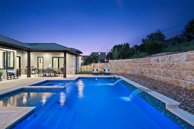 pool at dusk with pool water feature, ceiling fan, and a patio area