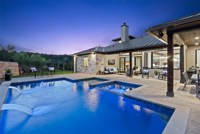 pool at dusk featuring an in ground hot tub and a patio area