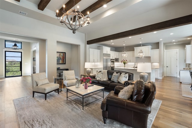 living room featuring beam ceiling, light hardwood / wood-style flooring, sink, and an inviting chandelier