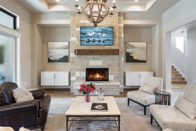 living room with a fireplace, a notable chandelier, hardwood / wood-style floors, and a raised ceiling