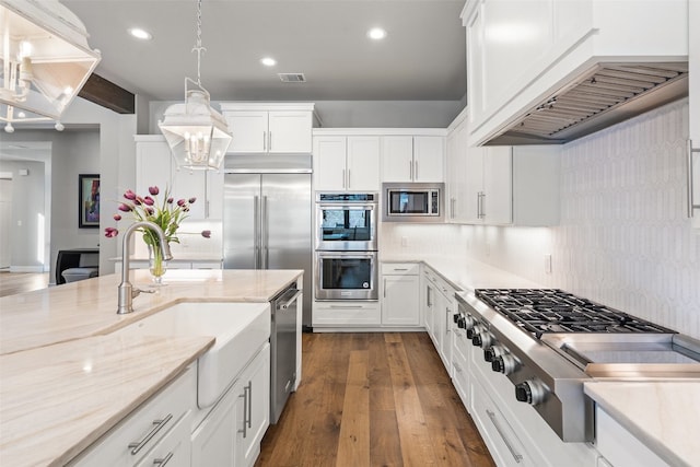 kitchen with white cabinetry, built in appliances, dark hardwood / wood-style flooring, decorative backsplash, and pendant lighting