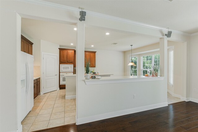 kitchen with pendant lighting, kitchen peninsula, white appliances, and light hardwood / wood-style floors