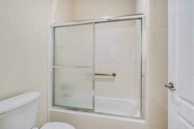 bathroom featuring enclosed tub / shower combo and toilet