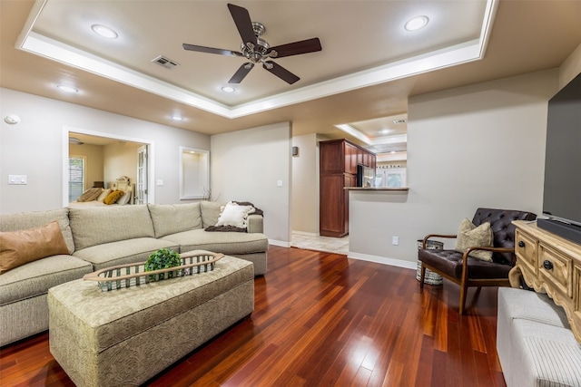 living room with ceiling fan, dark hardwood / wood-style floors, and a raised ceiling