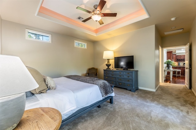 carpeted bedroom featuring a raised ceiling and ceiling fan