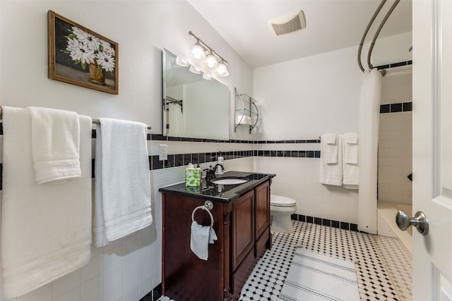 bathroom featuring tile walls, toilet, tiled shower, and vanity