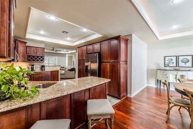 kitchen featuring ceiling fan, hardwood / wood-style floors, a tray ceiling, and stainless steel fridge with ice dispenser