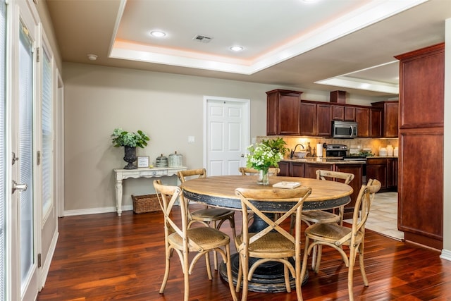 dining room featuring a tray ceiling and dark hardwood / wood-style flooring