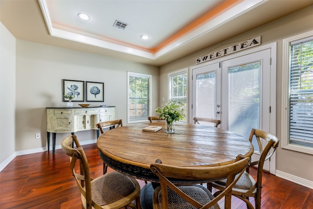 dining space featuring a tray ceiling, dark wood-type flooring, and french doors