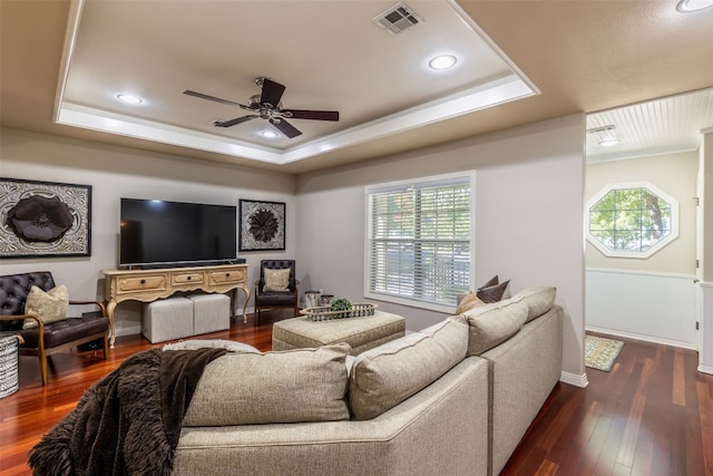 living room with dark wood-type flooring, a raised ceiling, and ceiling fan