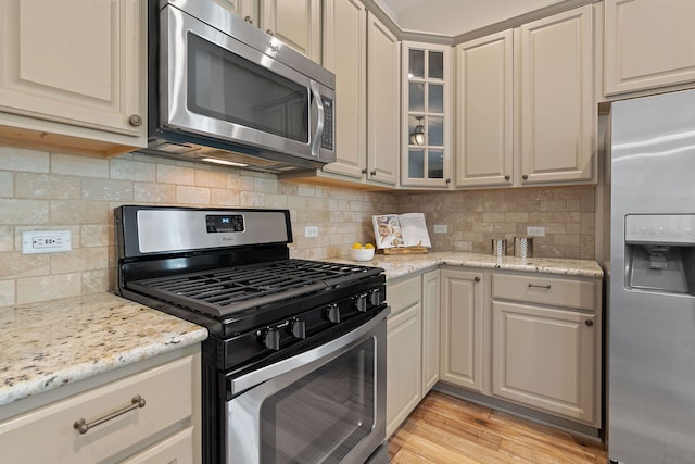 kitchen with light stone counters, backsplash, and stainless steel appliances