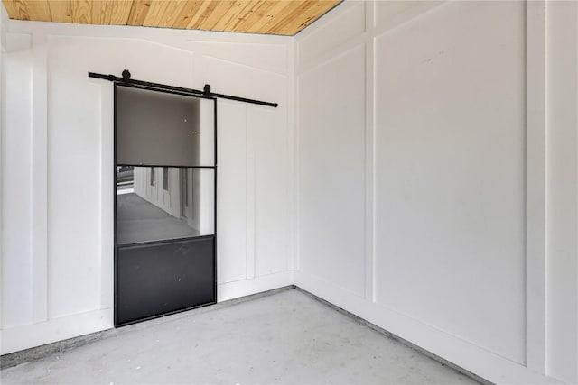 unfurnished room featuring a barn door, wooden ceiling, concrete flooring, and vaulted ceiling