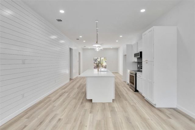 kitchen with ceiling fan, a center island, stainless steel appliances, light hardwood / wood-style flooring, and white cabinets