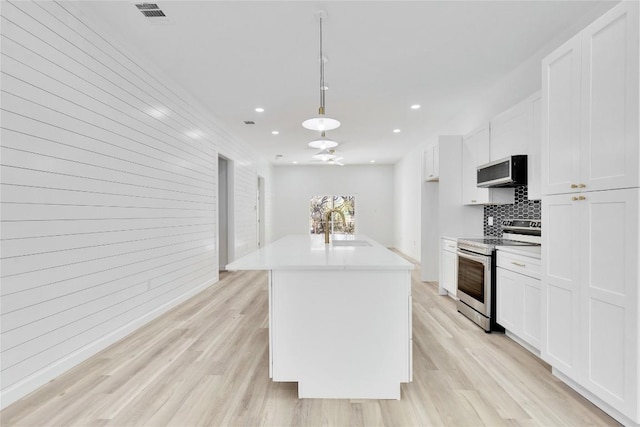 kitchen featuring appliances with stainless steel finishes, sink, a center island with sink, light hardwood / wood-style flooring, and white cabinets