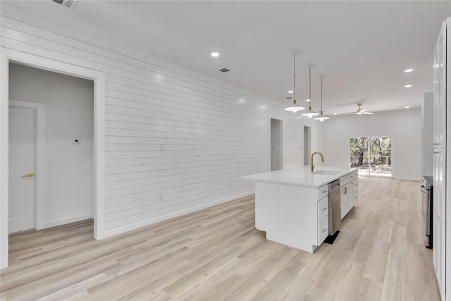 kitchen featuring sink, light hardwood / wood-style flooring, an island with sink, decorative light fixtures, and white cabinets