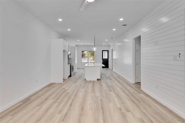 kitchen featuring white cabinets, decorative light fixtures, light wood-type flooring, and a center island