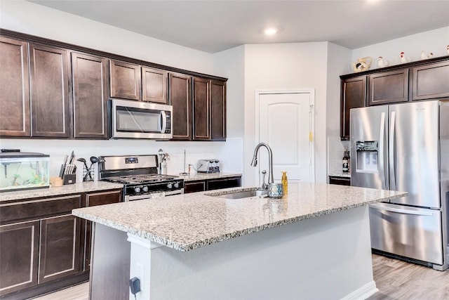 348 Empress Tree Dr, Leander, TX 78641 - kitchen featuring appliances with stainless steel finishes, a sink, dark brown cabinets, light stone countertops, and recessed lighting