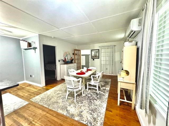 dining space featuring an AC wall unit and hardwood / wood-style floors