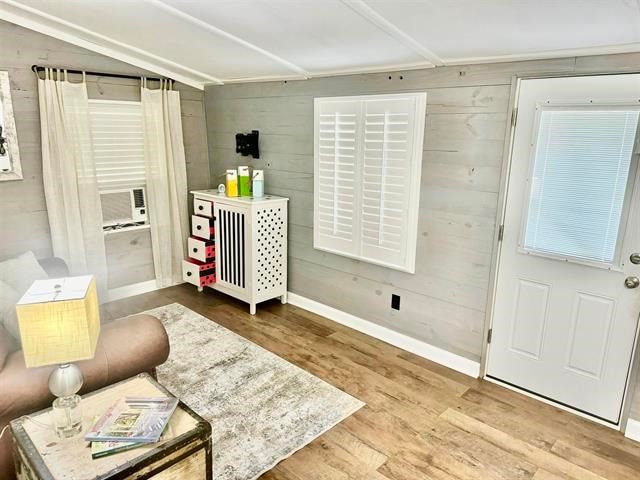 sitting room with lofted ceiling, wood walls, and hardwood / wood-style floors