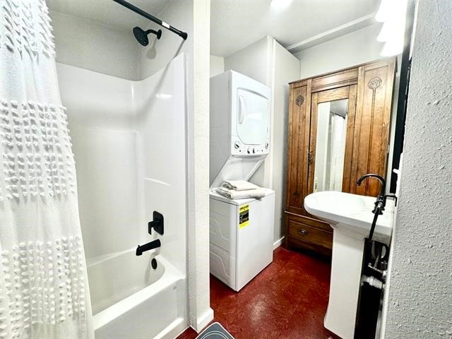 bathroom featuring shower / tub combo with curtain and stacked washer / drying machine