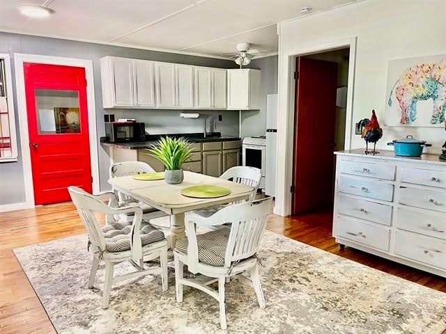 kitchen with wood-type flooring, electric range, sink, white cabinetry, and ceiling fan