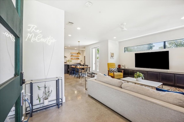 living room with ceiling fan and concrete flooring