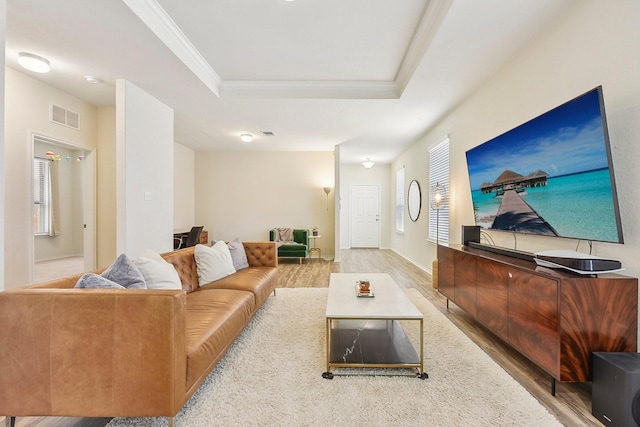 living room featuring hardwood / wood-style flooring, a tray ceiling, and ornamental molding