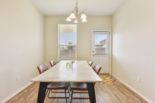 dining room with light wood-type flooring and an inviting chandelier