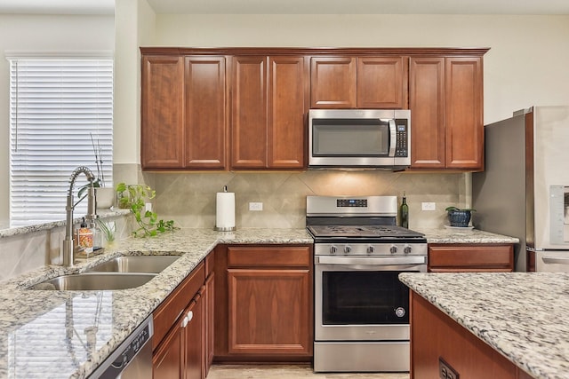 kitchen with light stone counters, a healthy amount of sunlight, decorative backsplash, appliances with stainless steel finishes, and sink