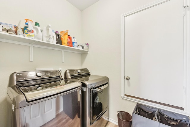 laundry area featuring washing machine and clothes dryer and light hardwood / wood-style floors