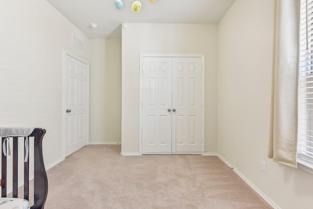 unfurnished bedroom with light colored carpet and a closet