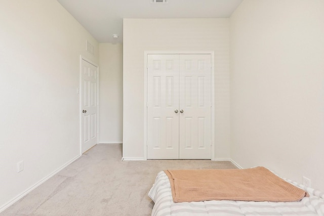 unfurnished bedroom with light colored carpet and a closet