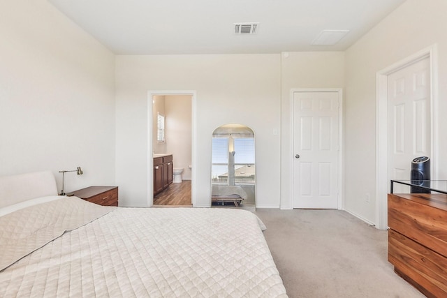 bedroom featuring light colored carpet and ensuite bathroom