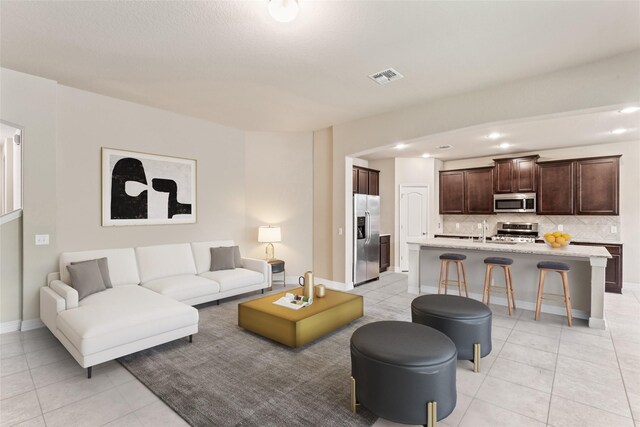 living room featuring sink and light tile patterned flooring