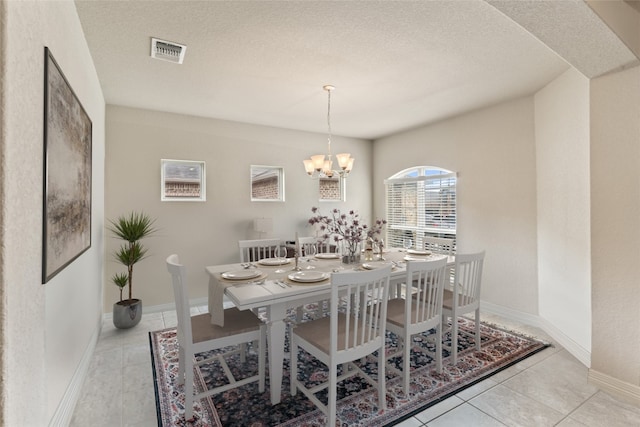 dining room with a textured ceiling, a notable chandelier, and light tile patterned floors