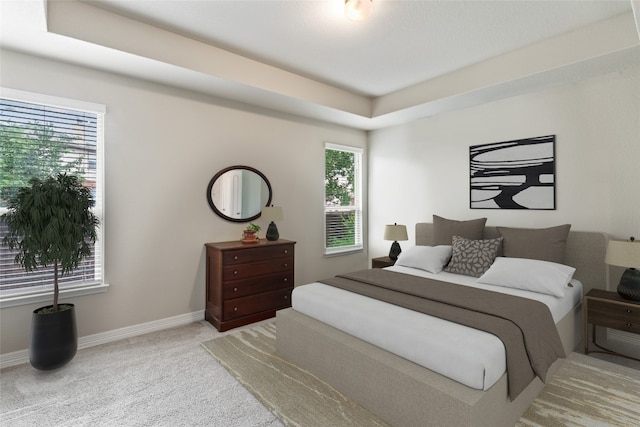 bedroom with light carpet and a tray ceiling