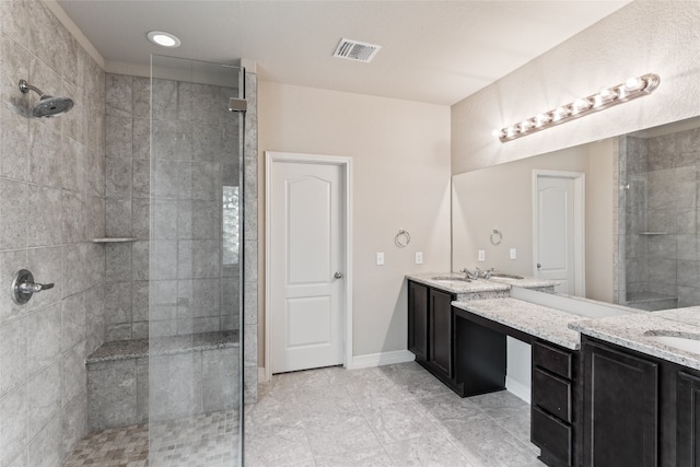 bathroom featuring dual vanity, tiled shower, and tile patterned floors