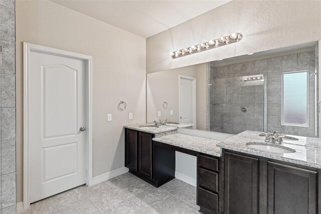 bathroom featuring a tile shower, tile patterned flooring, and dual bowl vanity