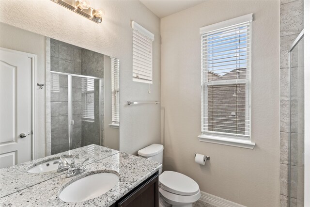 bathroom with a shower with shower door, vanity, and toilet