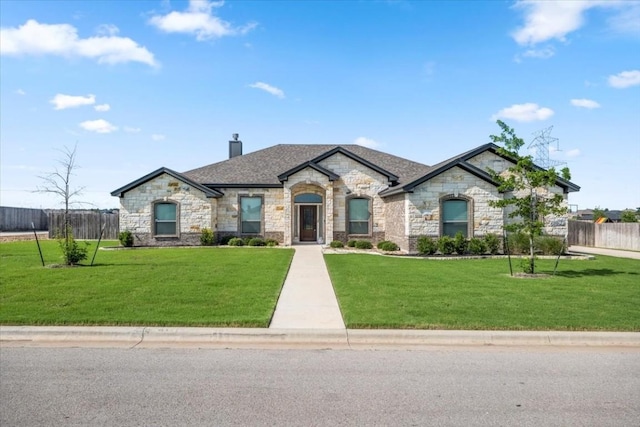 french provincial home featuring fence, a chimney, and a front lawn