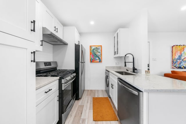 kitchen featuring appliances with stainless steel finishes, washer / clothes dryer, light hardwood / wood-style floors, sink, and white cabinetry